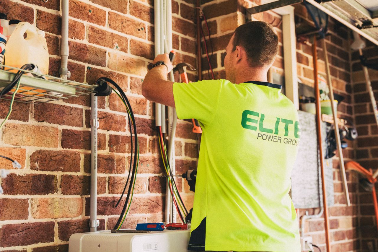 Mastering the First Impression: Your intriguing post title goes here Electrician performing solar battery installation for sustainable energy storage in a home setting.
